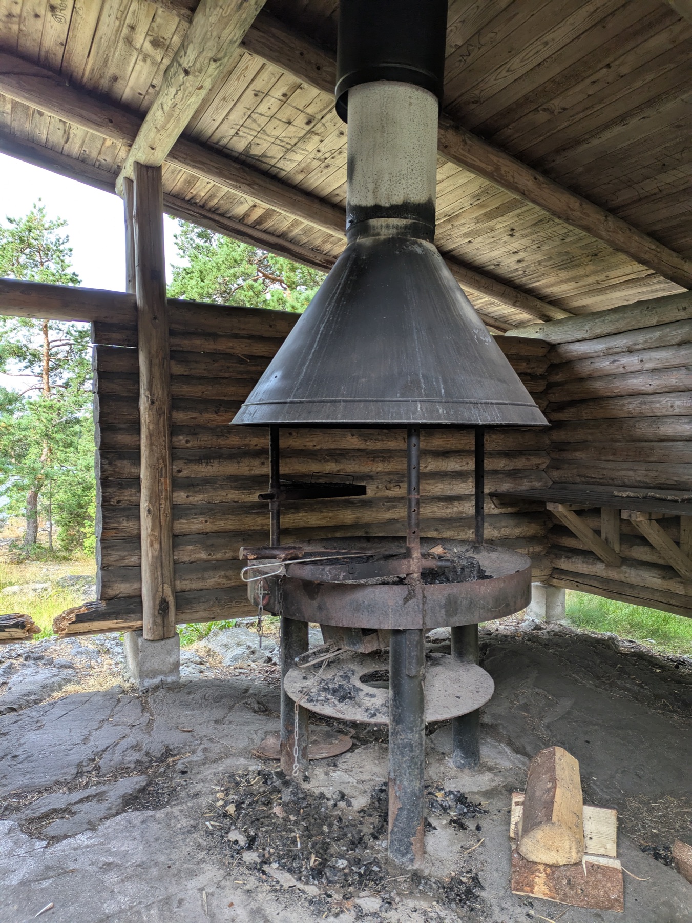 The central fireplace and chimney inside a log campfire shelter